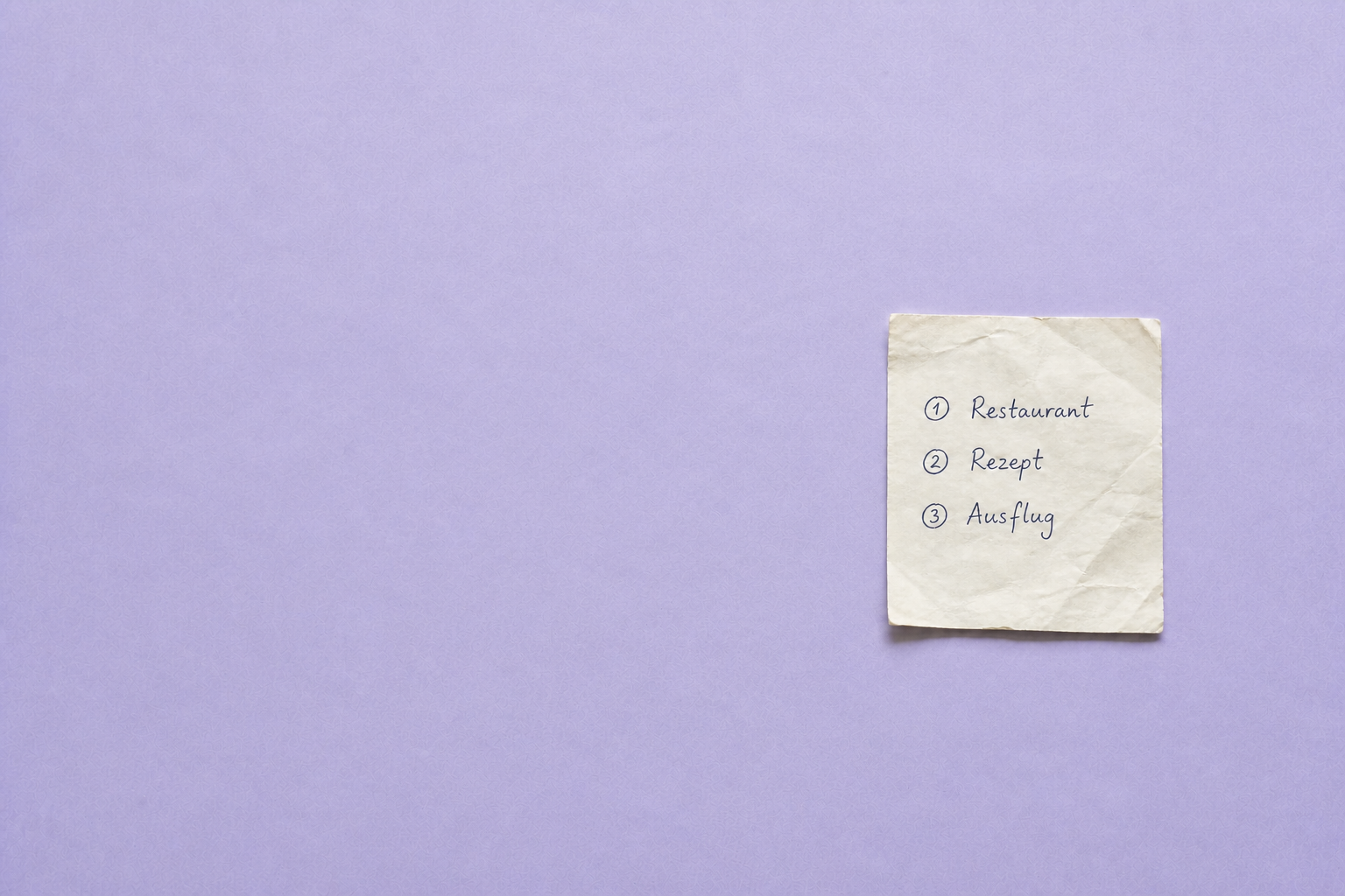 Handgeschriebene Liste mit Restaurant, Rezept und Ausflug auf einem Zettel
